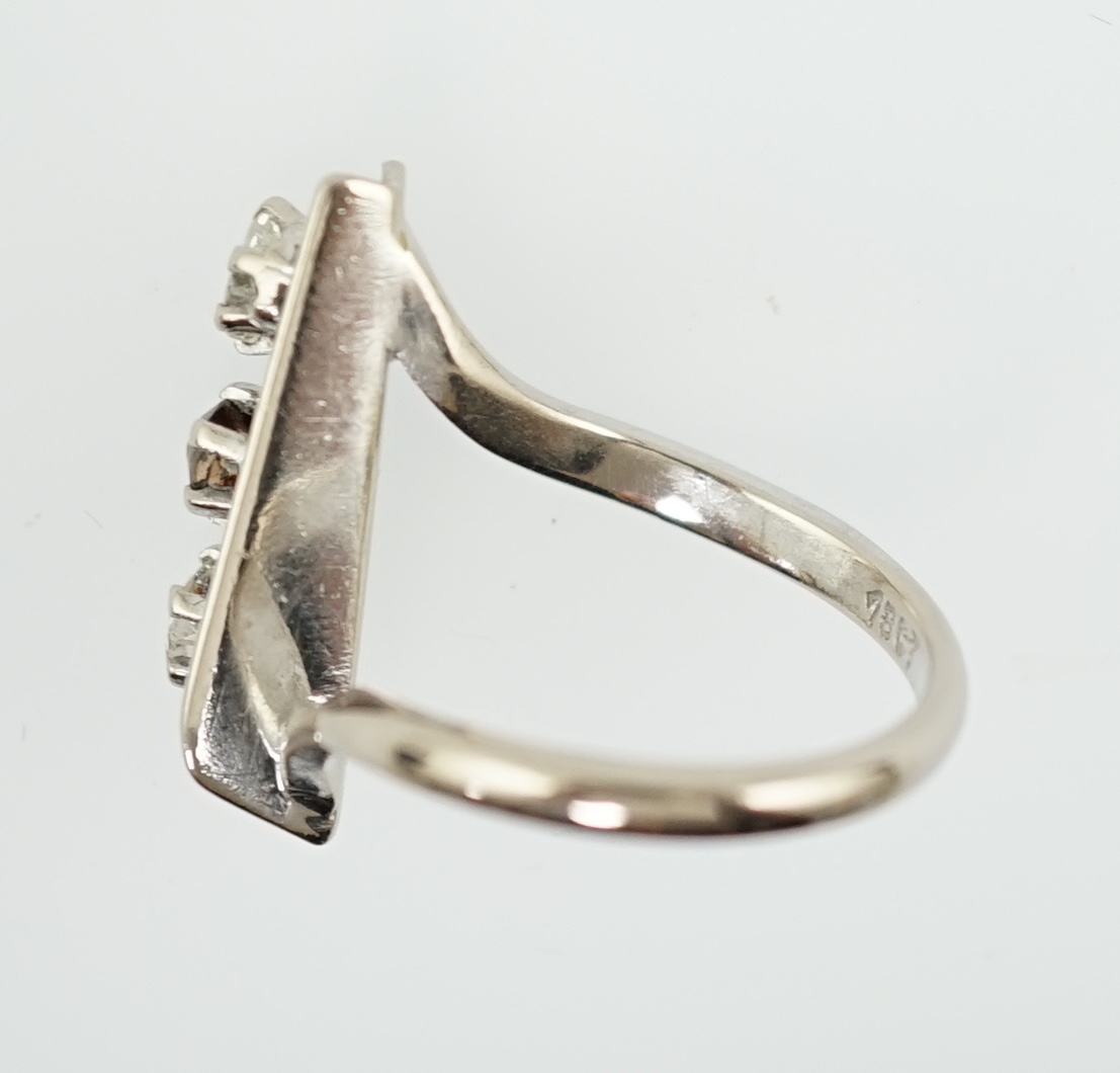 A 1970's 18ct white gold and graduated three stone diamond modernist ring